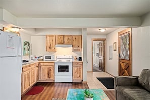 Una cocina compacta con muebles de madera, una estufa blanca y un microondas.