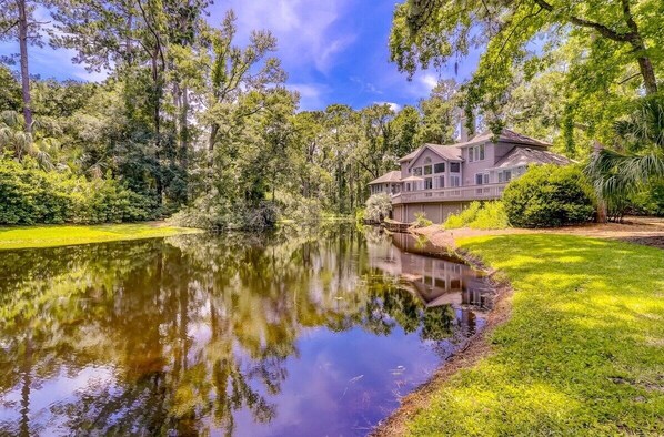 Overlooking the serene lake, this house offers a tranquil retreat surrounded by lush greenery and tall trees.