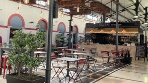 Un'area pranzo interna con tavoli e sedie, un bancone con il menu e lampade a sospensione.