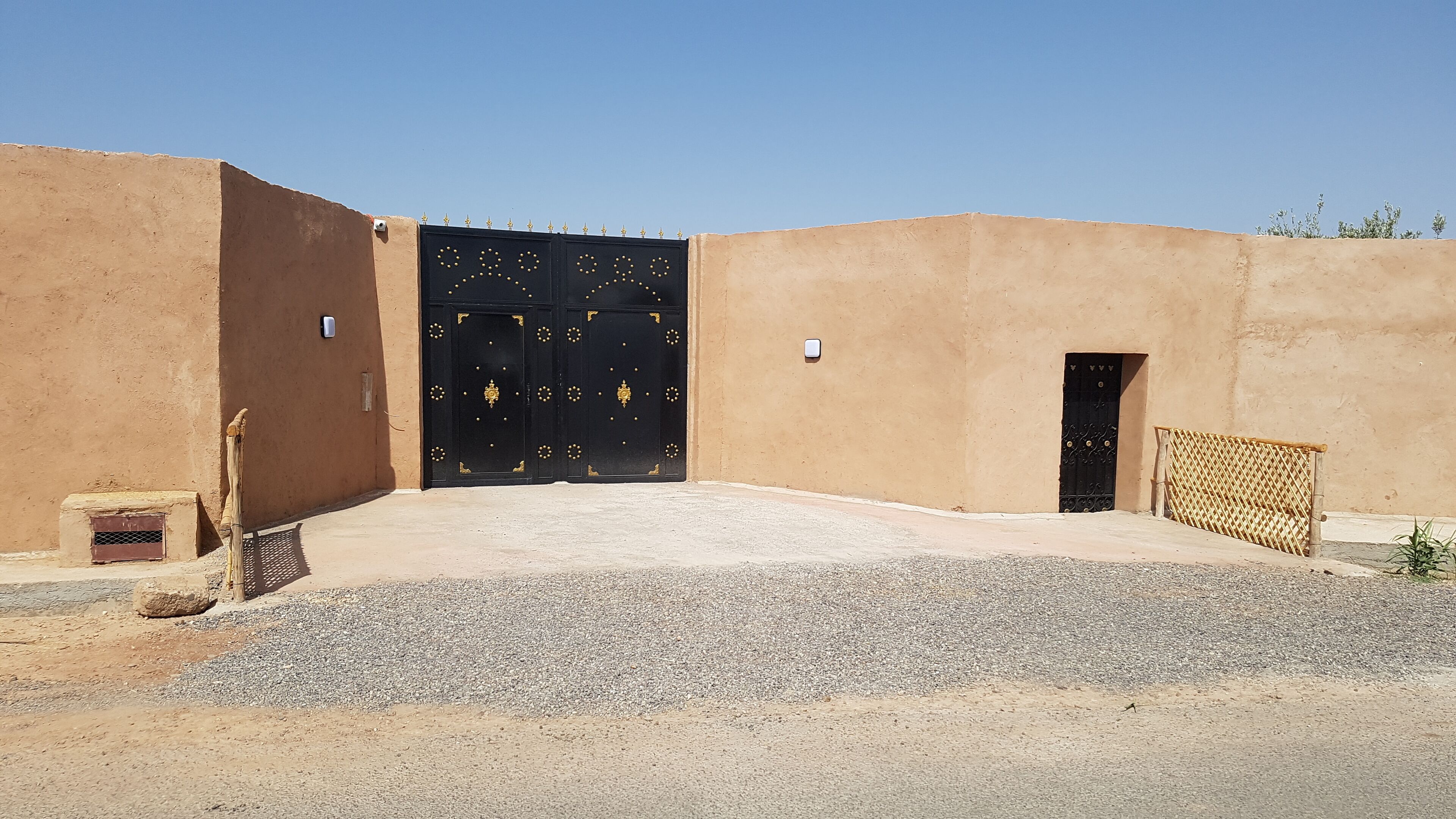 Un bâtiment doté d’un grand portail noir, d’une porte plus petite et d’un porche abrité.