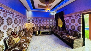 A room with patterned walls, a long sofa, and a chandelier. - Villa Salah (Marrakech)