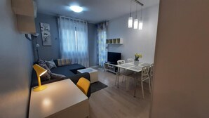 A compact living space with a bed, a desk, a dining table, and a TV.