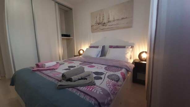 A neatly made bed with a floral bedspread, two bedside lamps, and a painting on the wall.