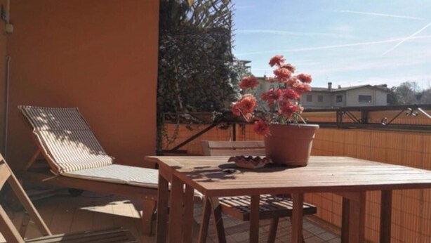 A wooden table with a potted plant, a striped lounge chair, and a wooden bench on a balcony. - Iseolake 1-bed Apartment in Provaglio D'iseo (Provaglio d'Iseo)