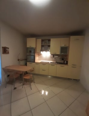 Une cuisine équipée d’une table et de chaises, de placards et d’un sol carrelé.