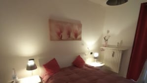 A bedroom with a bed, two bedside tables with lamps, a radiator, and a painting on the wall. - Iseolake 1-bed Apartment in Provaglio D'iseo (Provaglio d'Iseo)