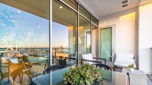 A modern hotel room with a glass table, a potted plant, and a view of the cityscape.