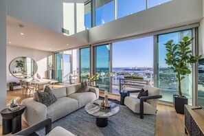 Ein großzügiger Wohnbereich mit einem großen Fenster und Blick auf die Stadt, einem runden Couchtisch und einem modernen Sofa.
