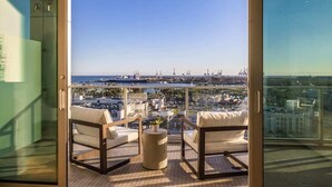 Un balcon avec deux chaises et une table, offrant une vue sur le paysage urbain et la mer.