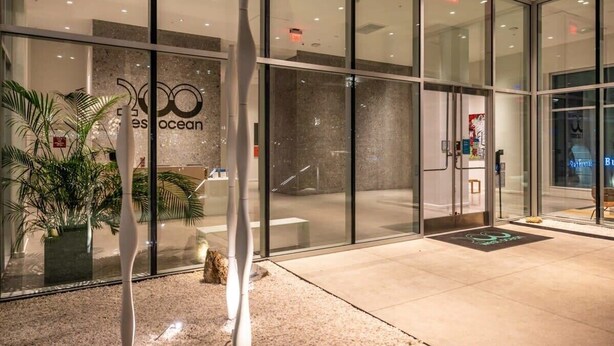 A modern hotel entrance with glass doors, a reception desk, and a sign reading "Ocean". - @ Marbella Lane - Luxury Beachside 2BR (Long Beach)