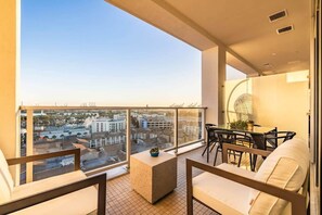 A balcony with a view of the city, a table with chairs, and a small plant.
