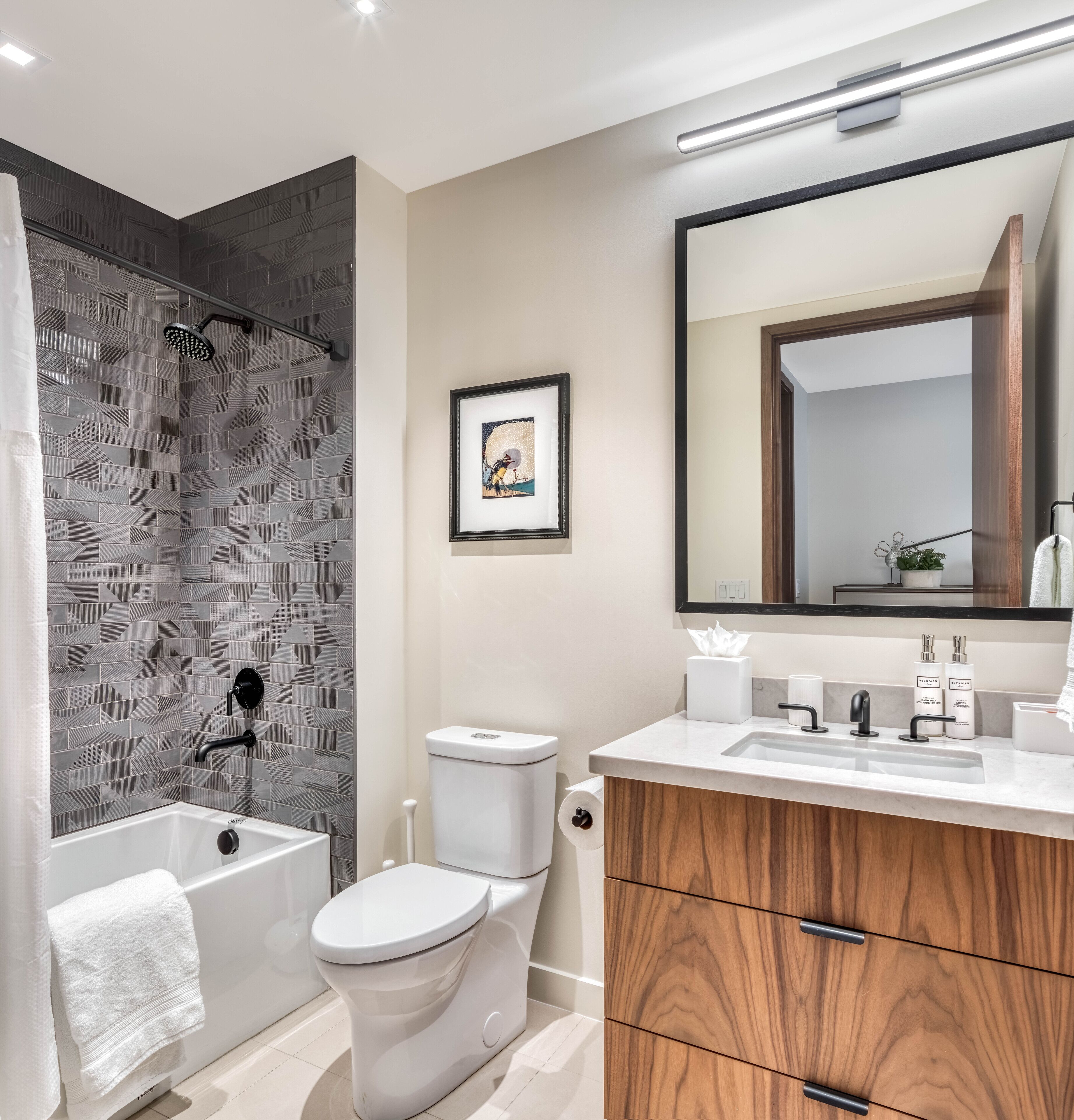 A modern bathroom with a shower, toilet, vanity, and a large mirror.