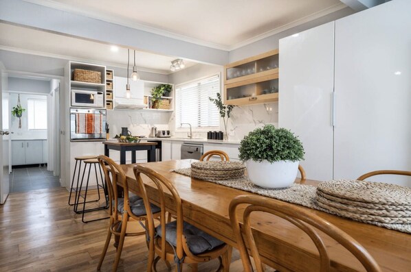 Modern kitchen with central island, microwave, oven, and dining area with table and chairs.