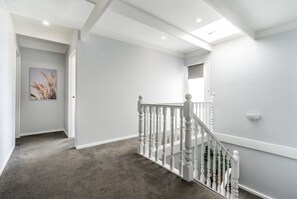 Stunning hallway with a white staircase, framed artwork, and recessed lighting.