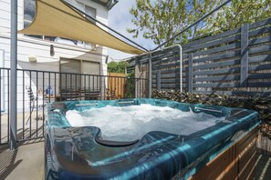 Relax in the hot tub on the outdoor patio, surrounded by a deck with a railing.