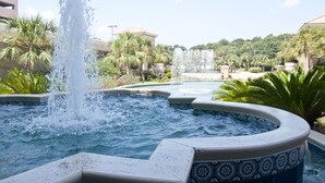 A hot tub area with multiple water jets, surrounded by palm trees and a pool. - Newly remodeled oceanfront condo close to everything (Myrtle Beach)