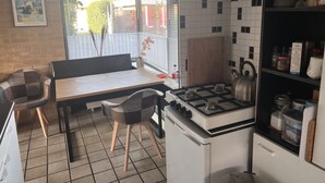 Una cucina compatta con piano cottura a gas, un piccolo frigorifero e un'area pranzo con tavolo e sedie.
