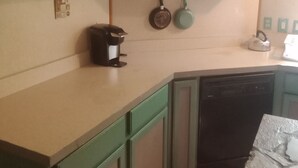Uma cozinha com armários verdes, uma cafeteira e uma chaleira no balcão.