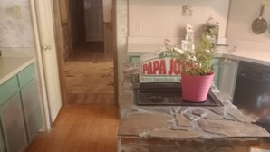 Uma cozinha com uma ilha de pedra, uma planta em vaso e uma placa com a inscrição PAPA JO.