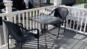 En terrasse med et bord og to stole, omkranset af et hvidt hegn.