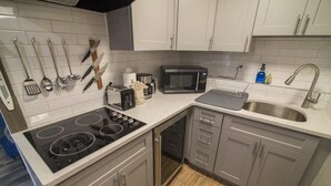 Een moderne keuken met een gasfornuis, magnetron, spoelbak en diverse keukengerei.