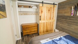 Een slaapkamer met een bed, een houten garderobe en een dressoir.