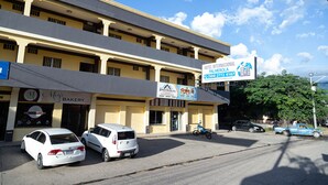 Um hotel com vários andares, com uma placa indicando 'Hotel Internacional Palma' e uma padaria chamada 'Mey's Bakery' no andar térreo.