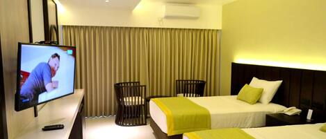 A hotel room with two beds, a TV, a desk, and a chair.