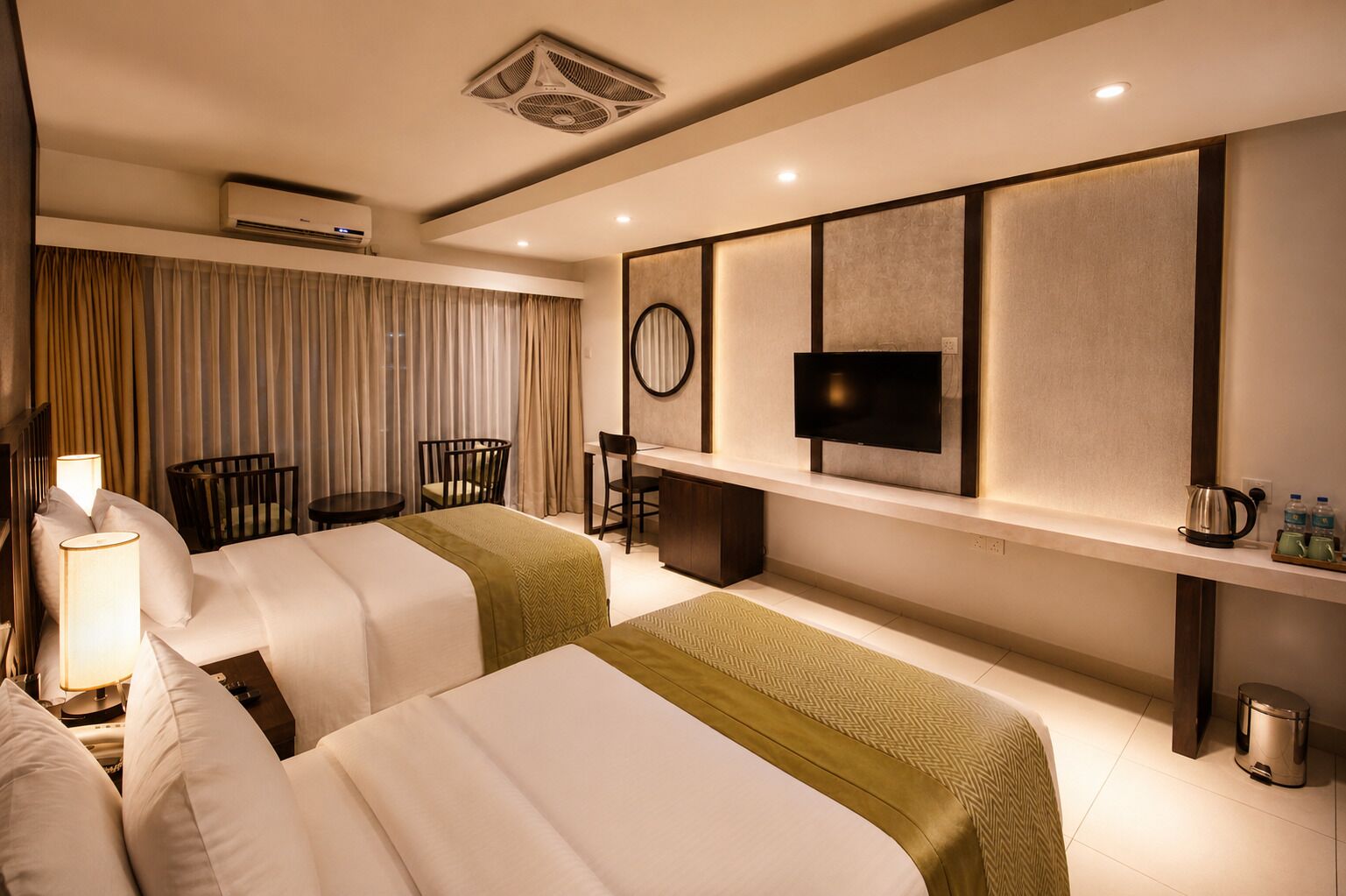 Ein Hotelzimmer mit zwei Betten, einem Schreibtisch, einem Sessel, einem Fernseher und einer Minibar.