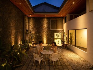 Une terrasse extérieure avec des murs en pierre, un plafond en bois et une table entourée de chaises.