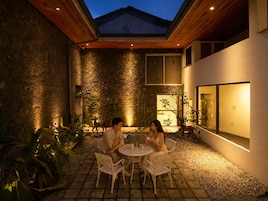 Un patio al aire libre con paredes de piedra, techo de madera y una mesa con sillas.