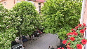 A street view with parked cars, trees, and pedestrians. - Unique Apartment Leninova (Skopje)