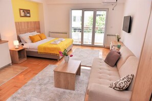 Une chambre d’hôtel moderne équipée d’un lit, d’un canapé, d’une table basse et d’un téléviseur.