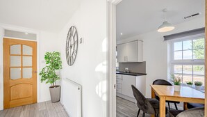 A modern kitchen with white cabinets, a wooden dining table, and a large window. - Carlisle - Apartment - Sleeps 5 - Pet-friendly (Carlisle)