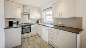A modern kitchen with white cabinetry, a gas stove, an oven, a microwave, and a window providing natural light. - Carlisle - Apartment - Sleeps 5 - Pet-friendly (Carlisle)