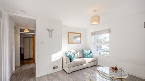 A modern living room with a beige sofa, a glass coffee table, and a wooden floor. - Carlisle - Apartment - Sleeps 5 - Pet-friendly (Carlisle)