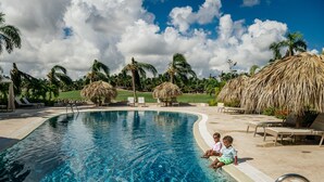 A clear swimming pool with lounge chairs and palm trees in the background. - Special offer for amazing apartment in Bavaro with the Wi-Fi, pool and security. (Bavaro)