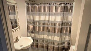 A bathroom with a striped shower curtain, a sink, and a toilet.