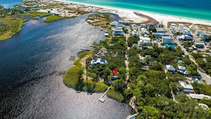 An aerial view of a coastal residential area with houses, a beach, and a marina.