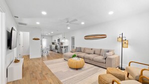 A modern living room with a sofa, ottomans, and a television.