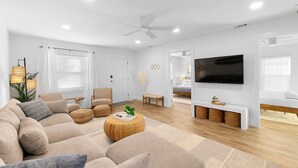 A modern living room with a sectional sofa, a flat-screen TV, and a ceiling fan.