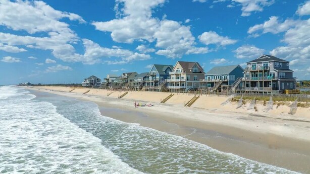 A beachfront hotel with multiple buildings, a sandy beach, and ocean waves. - beach front home pool  many new upgrades (North Topsail Beach)