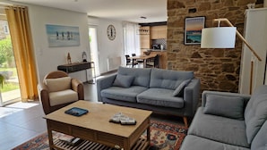 Een woonkamer met een bank, een salontafel en een eethoek met stoelen.