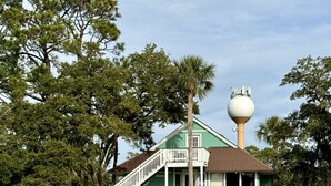 A two-story house with a green exterior, a white porch, and a satellite dish on the roof. - Tennis Courts in front, and the ever changing Marsh in back. Golf cart included. (Fripp Island)