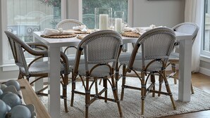 A dining area with a white table set for six, surrounded by wicker chairs, under a chandelier with hanging lights. - Tennis Courts in front, and the ever changing Marsh in back. Golf cart included. (Fripp Island)