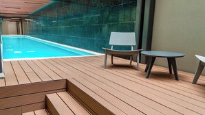 A wooden deck with a pool, a chair, and a table. - Luxury stay in Condesa | Rooftop, Pool & Views (Ciudad de México)