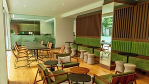 A modern lounge area with a large table, multiple seating options including sofas and chairs, and a green accent wall. - Luxury stay in Condesa | Rooftop, Pool & Views (Ciudad de México)