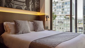 A hotel room with a large bed, a view of a modern building, and a decorative wall piece. - Luxury stay in Condesa | Rooftop, Pool & Views (Ciudad de México)