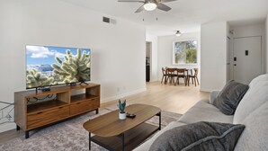 A modern living room with a flat-screen TV, wooden entertainment unit, and a ceiling fan. - Condo in Scottsdale (Scottsdale)