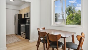 A modern kitchen with a dining area, a large window with a view of trees, and a wooden floor. - Condo in Scottsdale (Scottsdale)